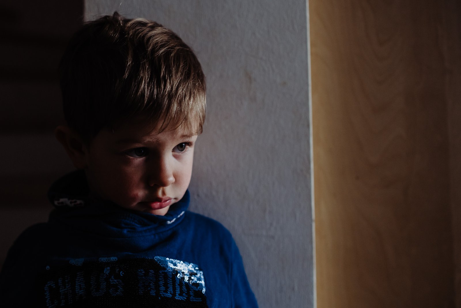 Ein Junge mit ernstem Gesichtsausdruck im seitlichen Fensterlicht.