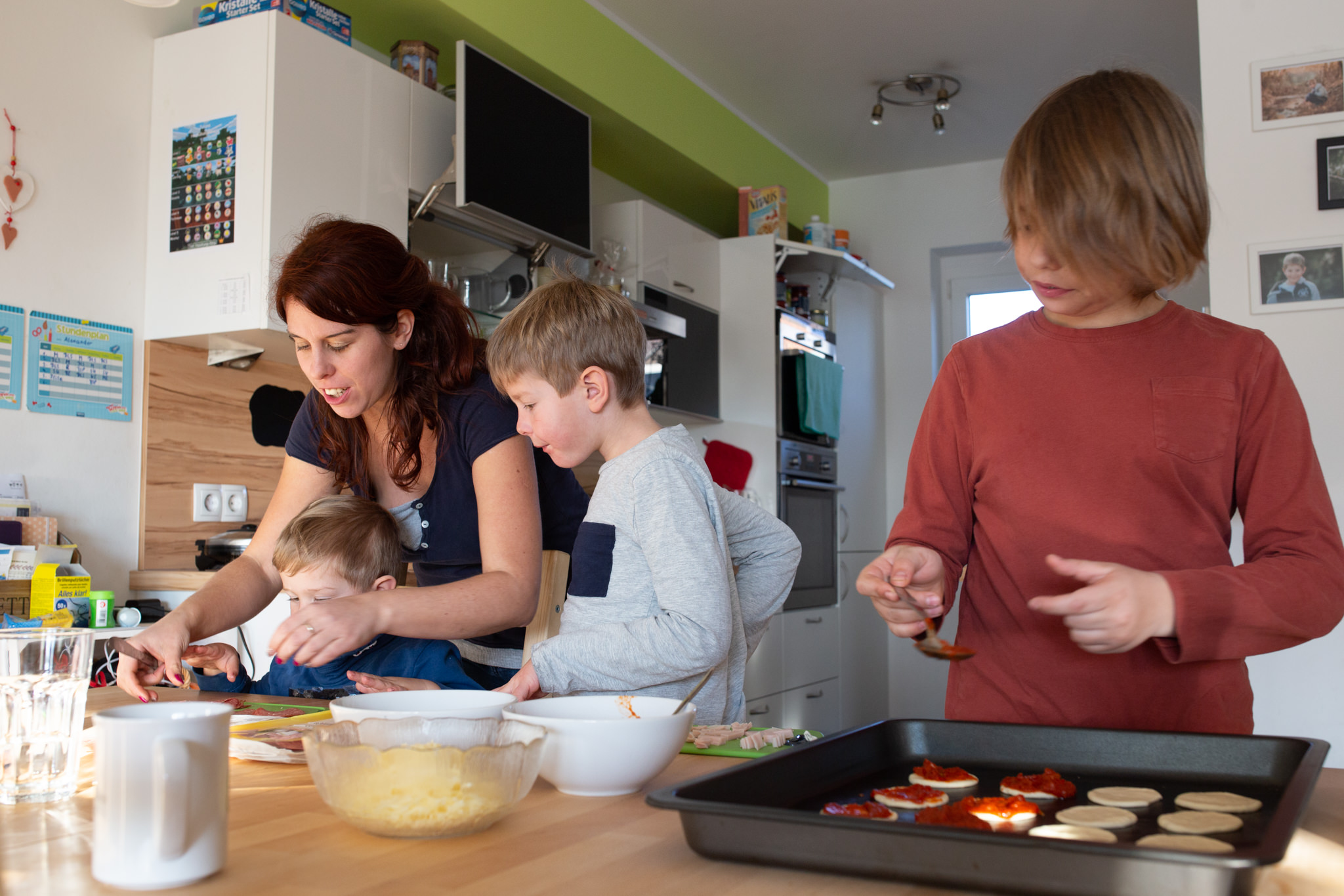 Eine Mutter bereitet mit ihren drei Kindern gemeinsam Essen in der Küche zu