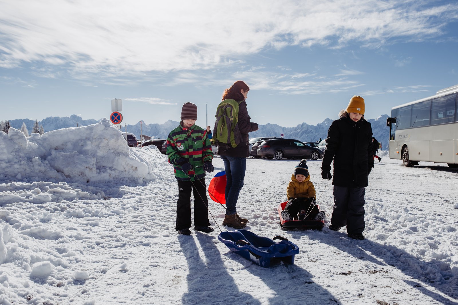 Die Familie steht mit ihren Schlitten auf dem verschneiten Berg.