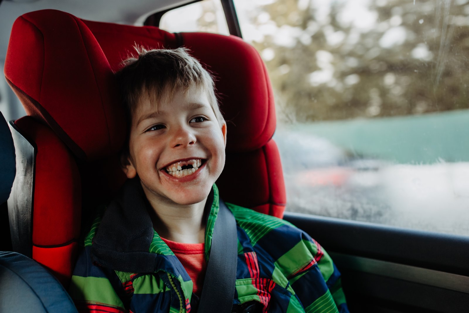 Ein Junge lacht in seinem Kindersitz im Auto.