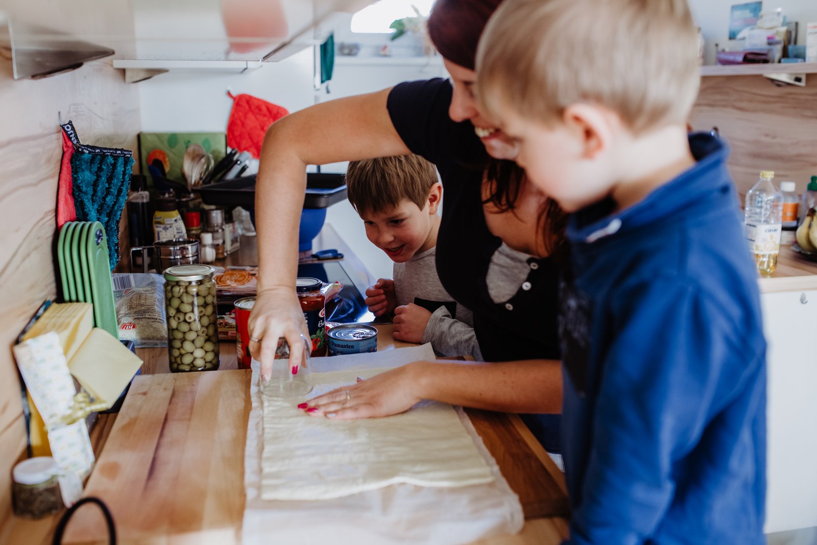 Die Kinder bereiten gemeinsam Pizza am Küchentisch zu.
