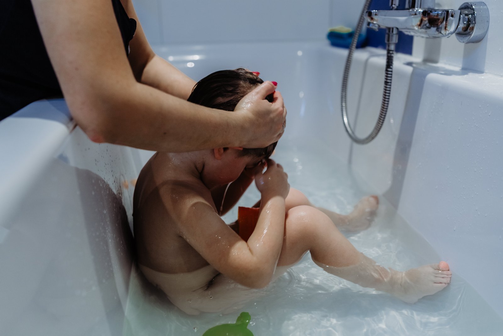 Einem Kind werden in der Badewanne die Haare gewaschen.