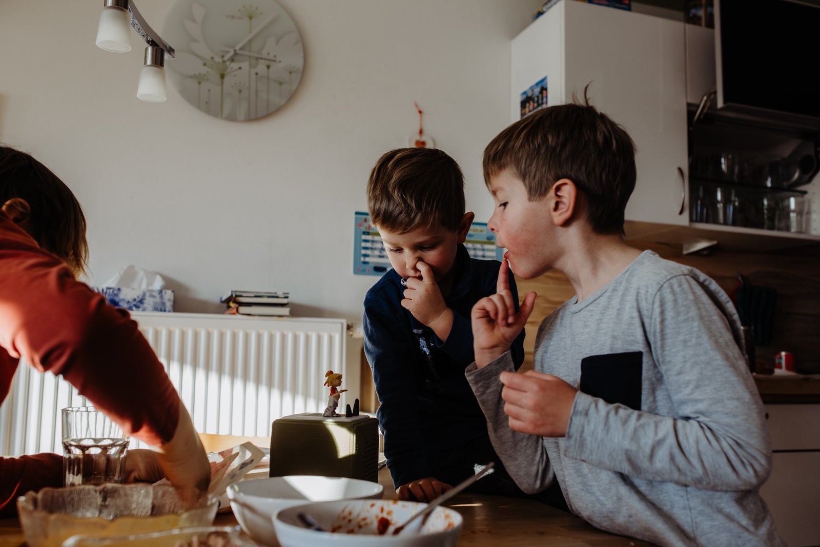 Mutter und Kinder stehen beim Pizzabacken zusammen am Tisch.