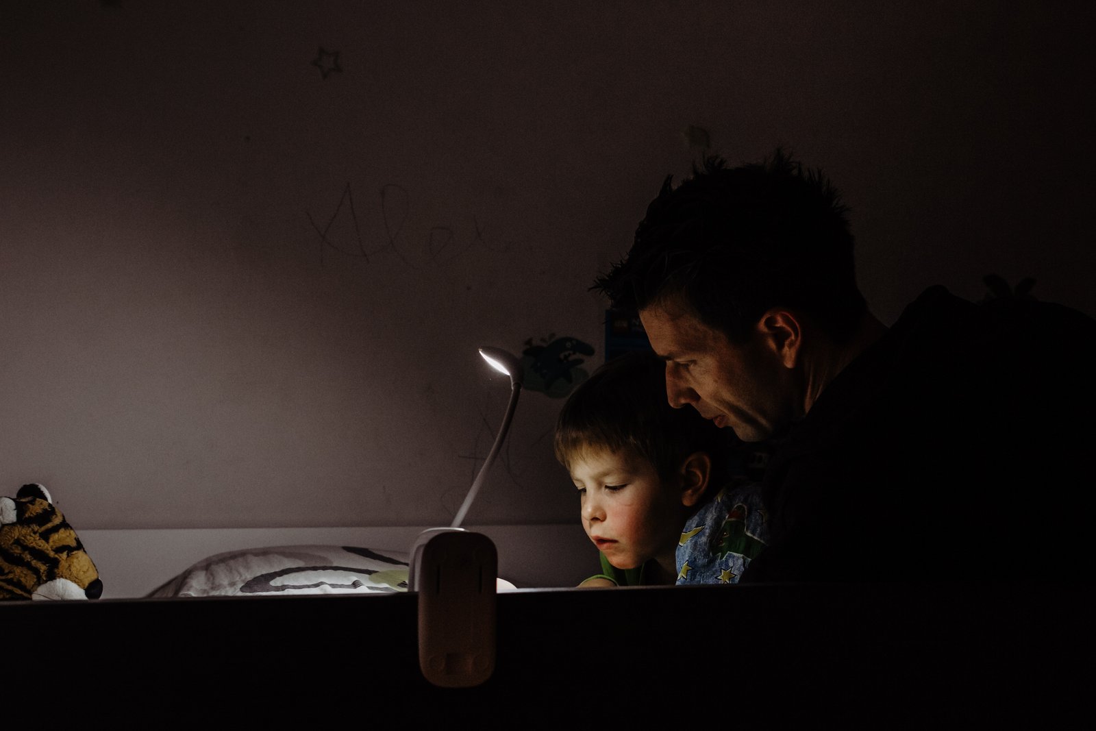 Ein Vater und sein Sohn lesen im Licht einer Lampe.